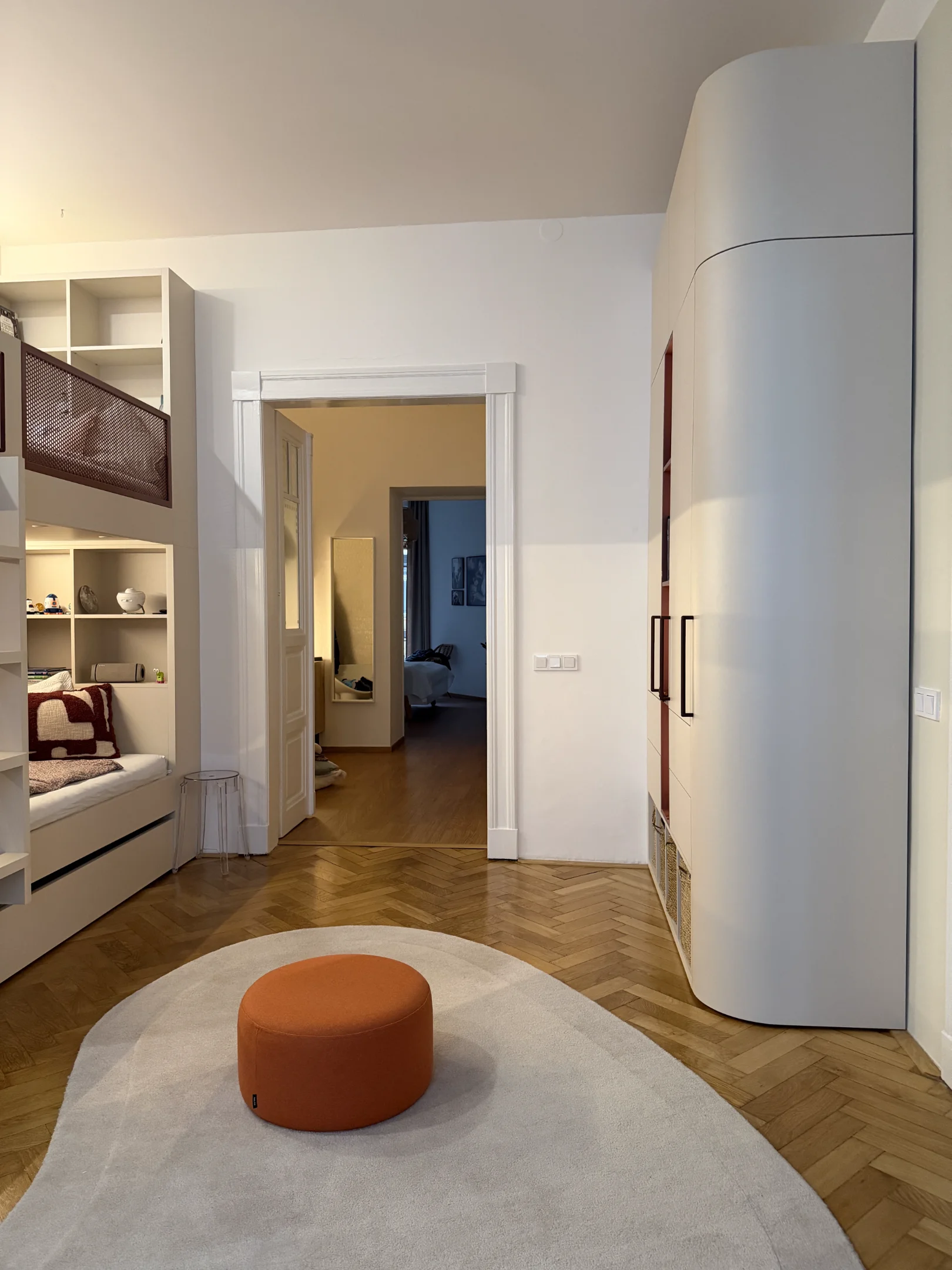 Moderní interiér s patrovou postelí, skříní a dřevěnou podlahou.